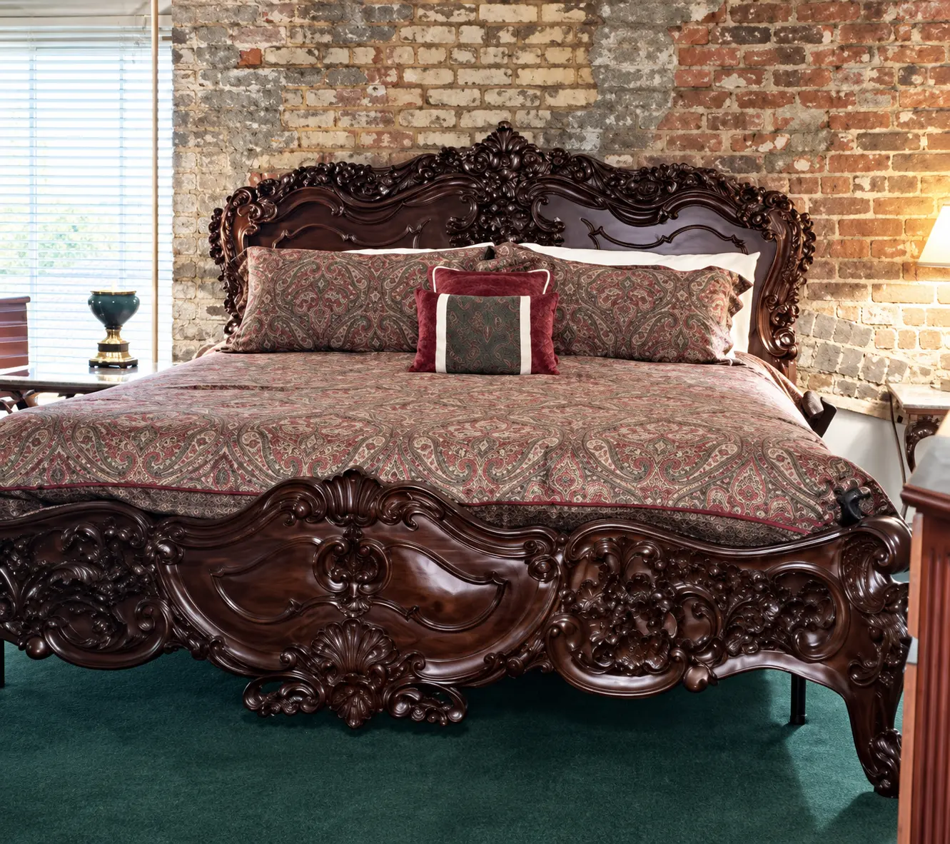 Ornate wooden bed and exposed brick walls in a guest suite at Plaza Suite Resort, a boutique hotel in New Orleans